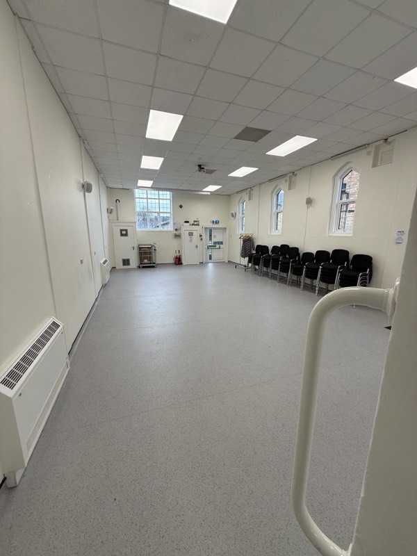 The main hall with chairs set out along a wall of arched windows