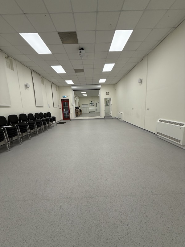 The hall with the roller shutter raised, opening through to the room beyond